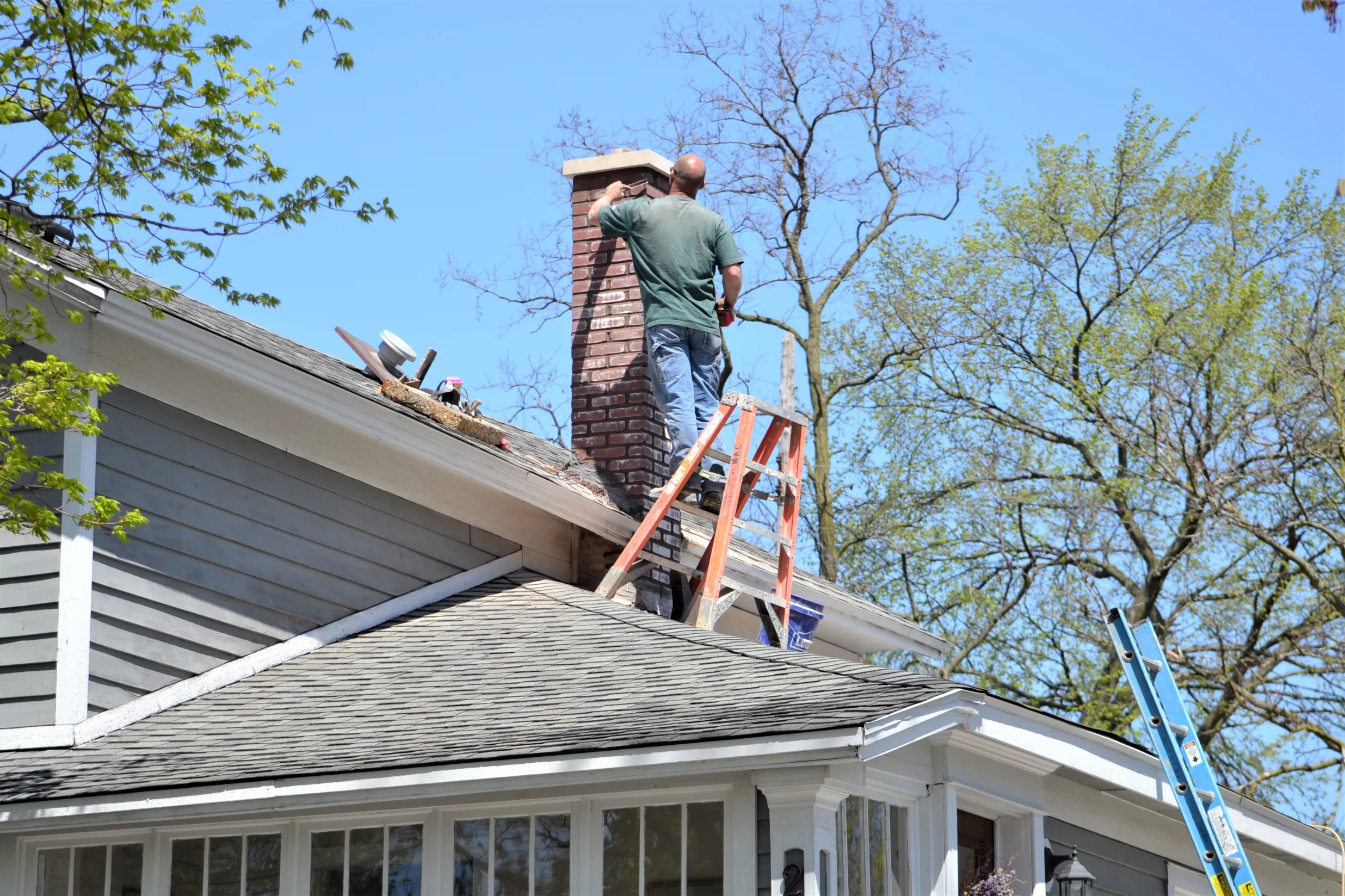 Man repairing a brick chimney on a sunny day